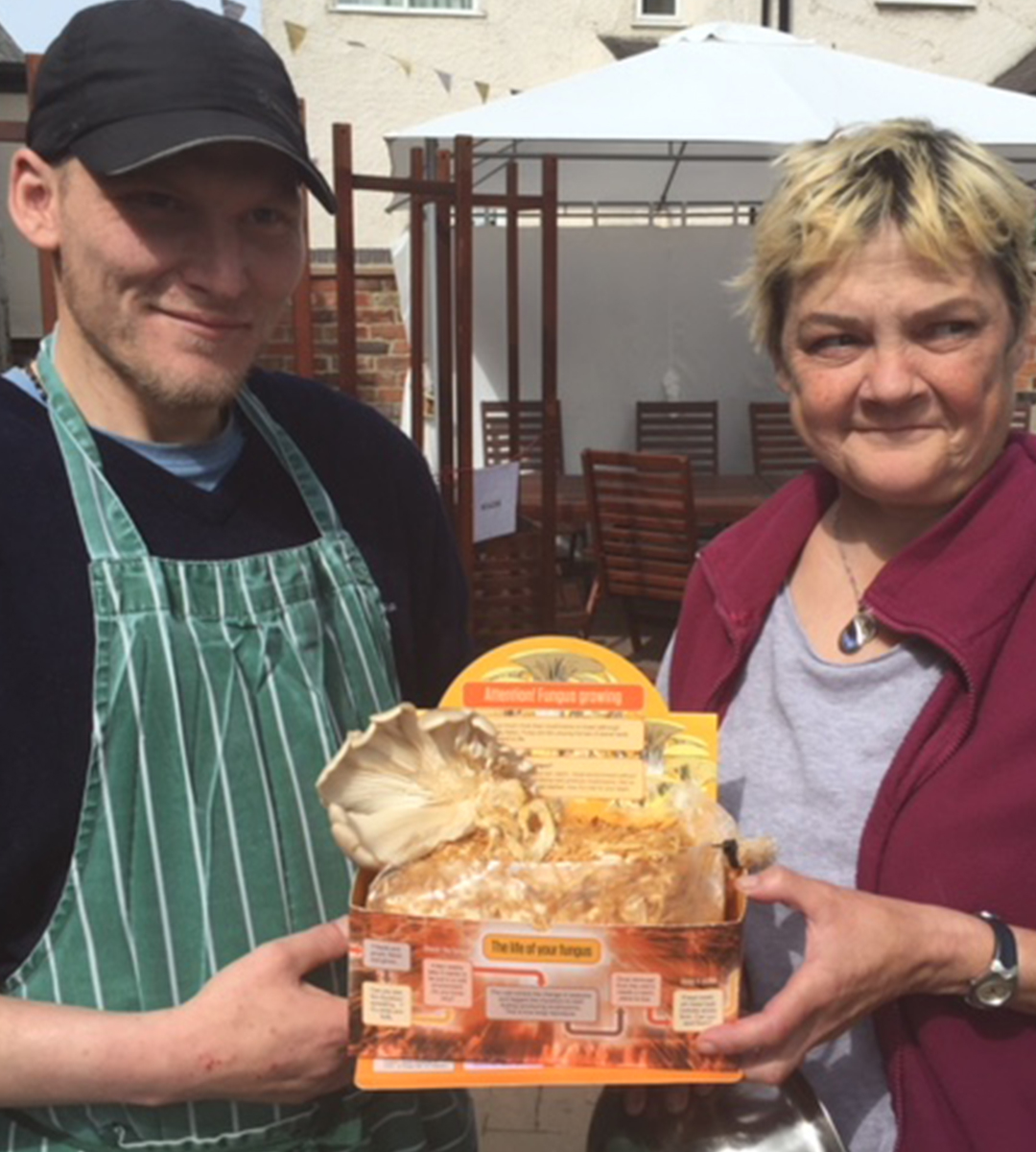 Two people at Growing Lives showing their fungus growing project